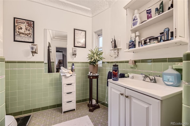 bathroom with vanity, a textured ceiling, tile patterned floors, and tile walls