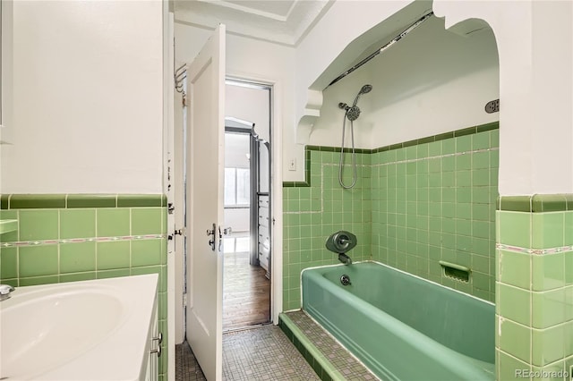 bathroom with tile patterned floors, tile walls, vanity, and tiled shower / bath combo