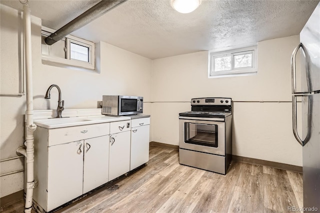 kitchen featuring white cabinets, sink, light hardwood / wood-style flooring, a textured ceiling, and appliances with stainless steel finishes