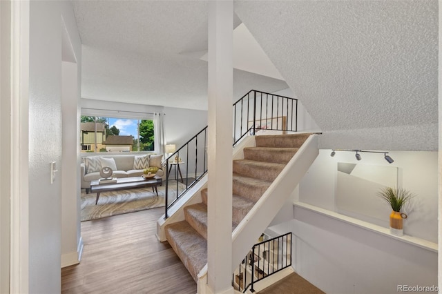 staircase with wood-type flooring and lofted ceiling