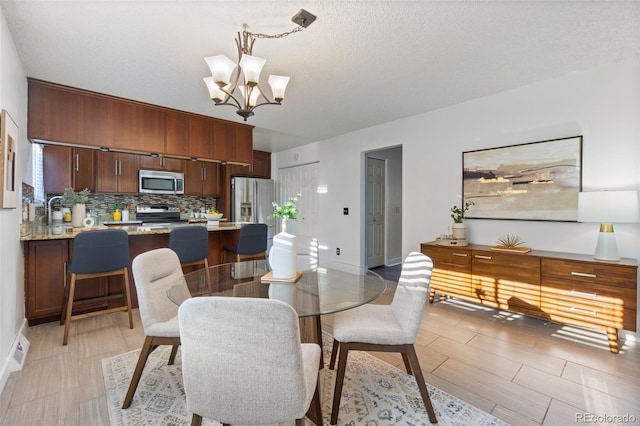 dining space with a textured ceiling and a notable chandelier