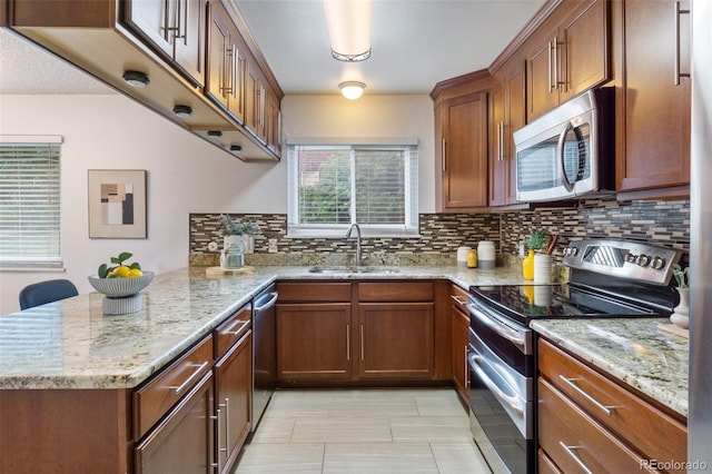 kitchen with appliances with stainless steel finishes, tasteful backsplash, light stone counters, and sink