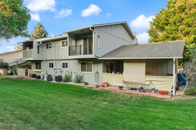 back of property with a yard, central air condition unit, and a balcony