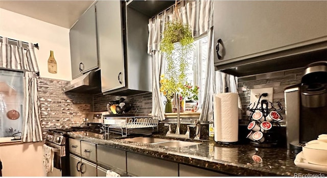 kitchen with backsplash, high end range, dark stone counters, gray cabinets, and ventilation hood