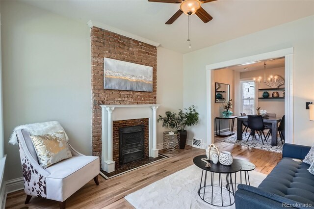 2564 N Emerson St, Denver, CO 80205 - living room featuring ceiling fan, wood finished floors, a brick fireplace, a chandelier, and baseboards