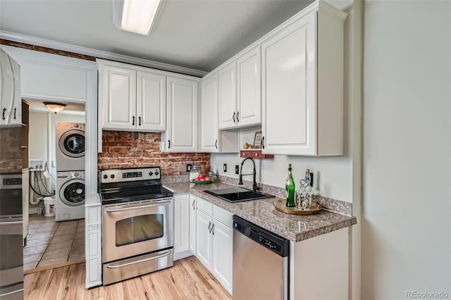 2564 N Emerson St, Denver, CO 80205 - kitchen with stainless steel appliances, stacked washer and clothes dryer, a sink, and white cabinetry