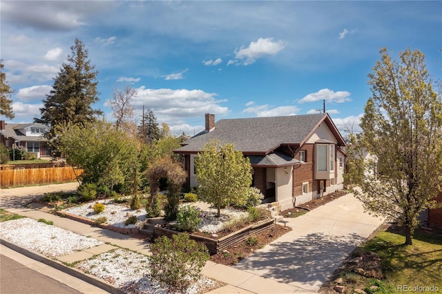 view of front of house featuring fence, a shingled roof, driveway, and a chimney