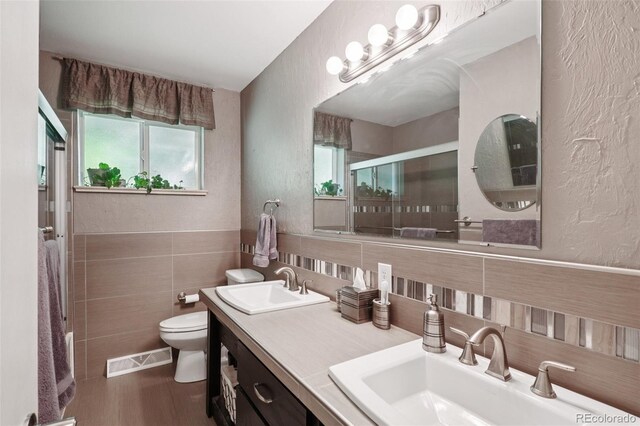13140 W 15th Dr, Golden, CO 80401 - full bathroom featuring a shower with shower door, tile walls, double vanity, a textured wall, and wood finished floors