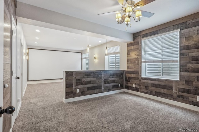 carpeted spare room featuring ceiling fan and wooden walls