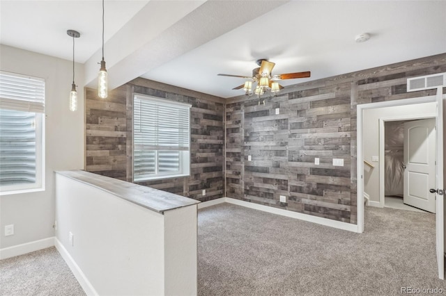 kitchen with carpet flooring, decorative light fixtures, wood walls, and ceiling fan