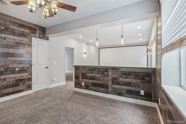 spare room with carpet, ceiling fan, and wooden walls