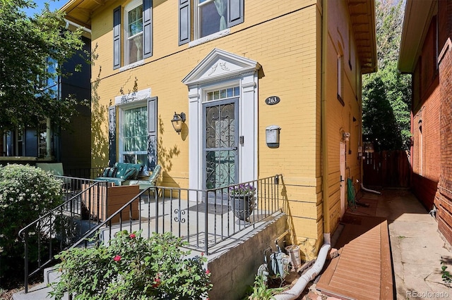 property entrance featuring brick siding and fence