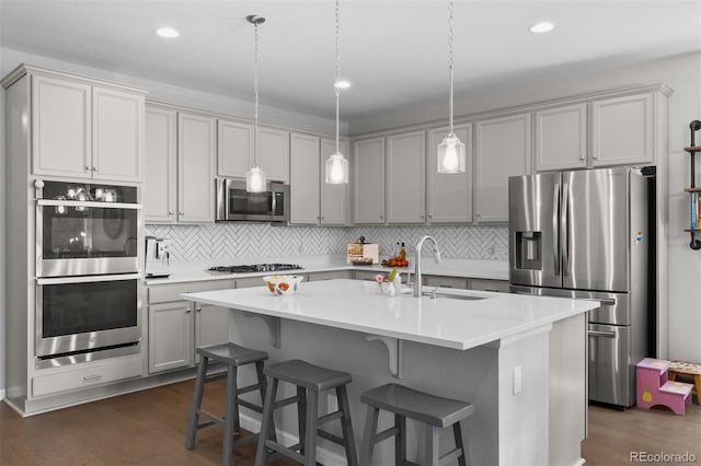 3575 White Rose Loop, Castle Rock, CO 80108 - kitchen featuring appliances with stainless steel finishes, a sink, backsplash, dark wood-style flooring, and a center island with sink