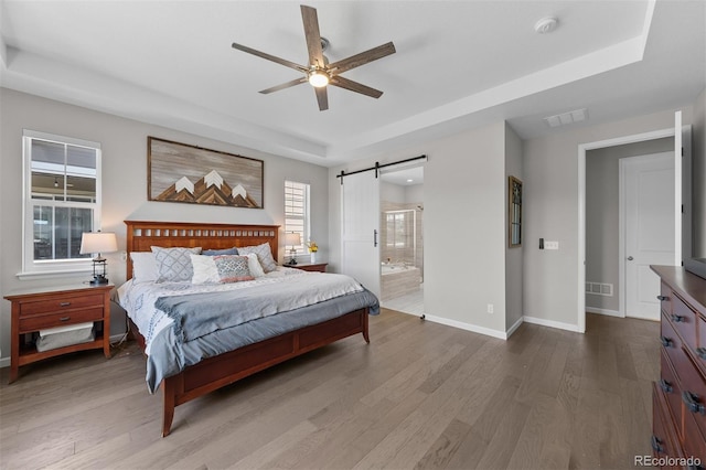 3575 White Rose Loop, Castle Rock, CO 80108 - bedroom featuring a raised ceiling, a barn door, wood finished floors, and baseboards
