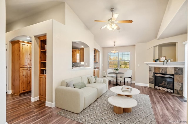 living room featuring ceiling fan, lofted ceiling, dark wood-type flooring, and a tile fireplace