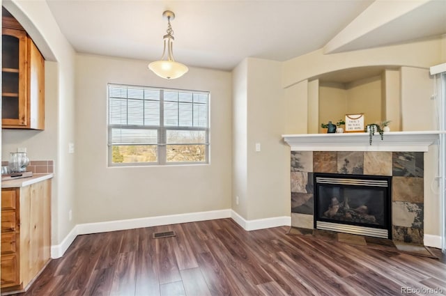 unfurnished living room with dark wood-type flooring and a tiled fireplace