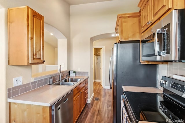 kitchen featuring stainless steel appliances, tasteful backsplash, dark wood-type flooring, and sink