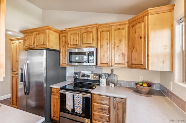 kitchen with backsplash, vaulted ceiling, and appliances with stainless steel finishes