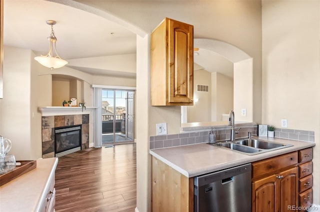 kitchen featuring pendant lighting, a tile fireplace, sink, stainless steel dishwasher, and dark hardwood / wood-style floors