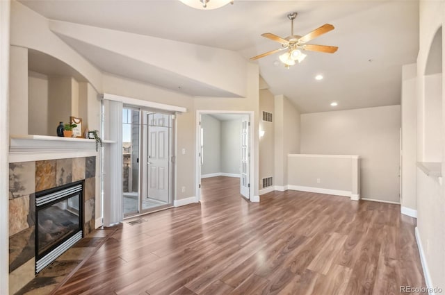 unfurnished living room with a tile fireplace, wood-type flooring, high vaulted ceiling, and ceiling fan