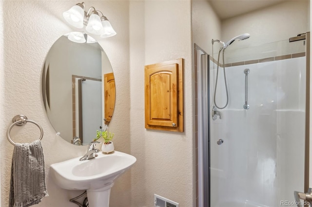 bathroom with a shower with door and sink