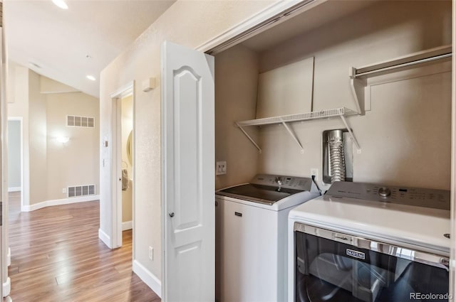 washroom with independent washer and dryer and light hardwood / wood-style floors