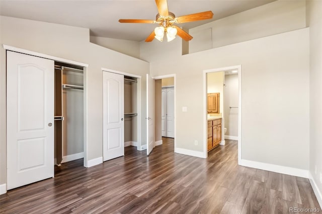 unfurnished bedroom with connected bathroom, ceiling fan, dark wood-type flooring, and lofted ceiling