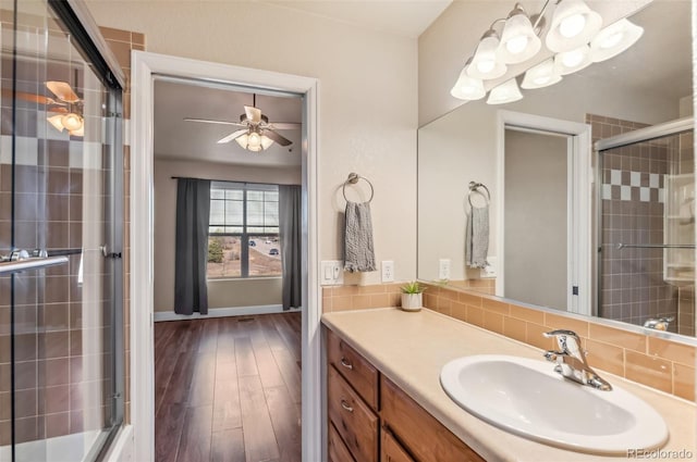 bathroom with hardwood / wood-style flooring, vanity, a shower with shower door, and tasteful backsplash