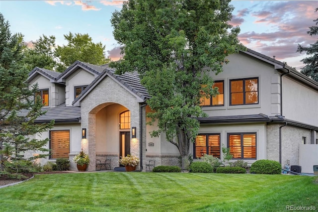 view of front facade featuring a front lawn, brick siding, and stucco siding