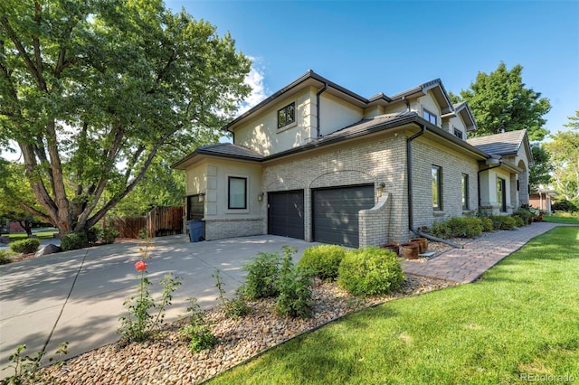 view of side of home with driveway, fence, brick siding, a garage, and a yard