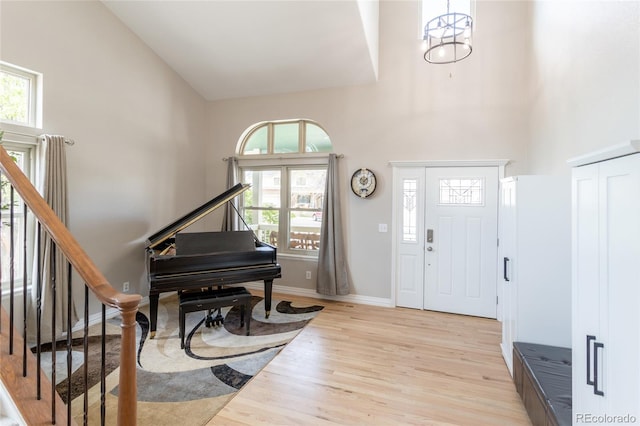 entrance foyer with a high ceiling, a healthy amount of sunlight, stairway, and light wood-style floors