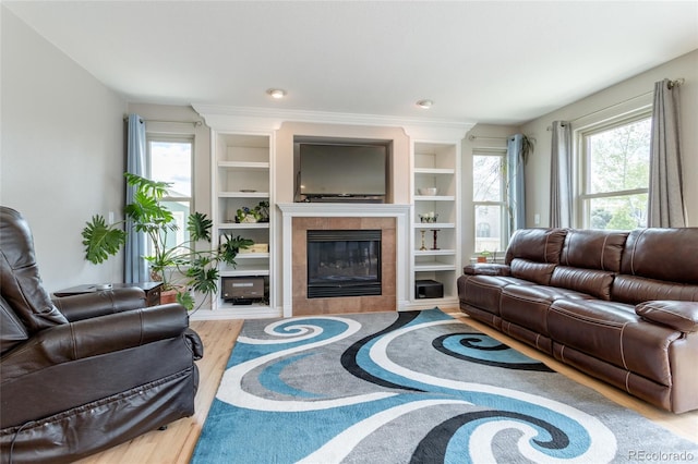 living room with built in shelves, wood finished floors, and a fireplace