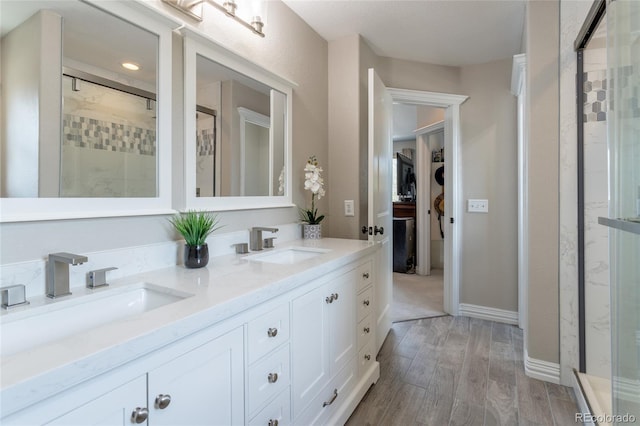 full bath with wood finished floors, double vanity, a sink, and a stall shower