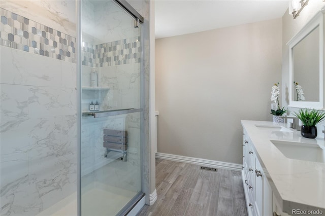 full bath with a marble finish shower, wood finished floors, and visible vents