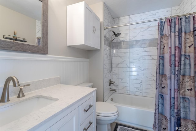 bathroom featuring vanity, a wainscoted wall, shower / bath combination with curtain, and toilet
