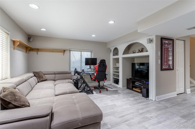 living room with visible vents, baseboards, light wood-style floors, recessed lighting, and built in shelves