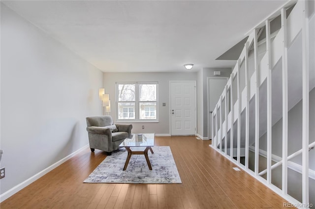 living area with hardwood / wood-style flooring, stairway, and baseboards