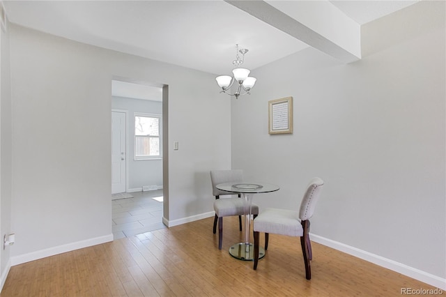 dining area featuring a notable chandelier, baseboards, and wood finished floors