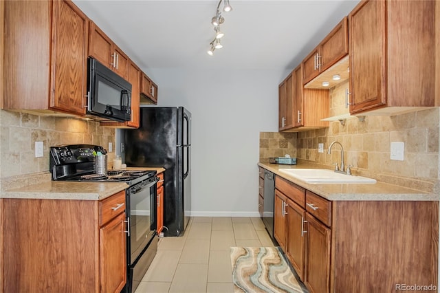 kitchen featuring tasteful backsplash, light countertops, a sink, black appliances, and baseboards