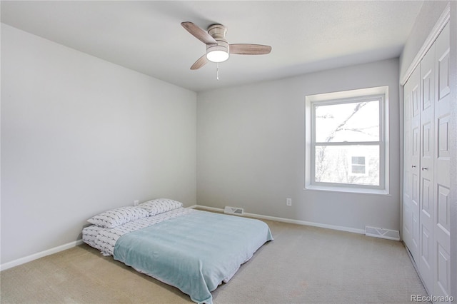 bedroom with a closet, light colored carpet, visible vents, and baseboards