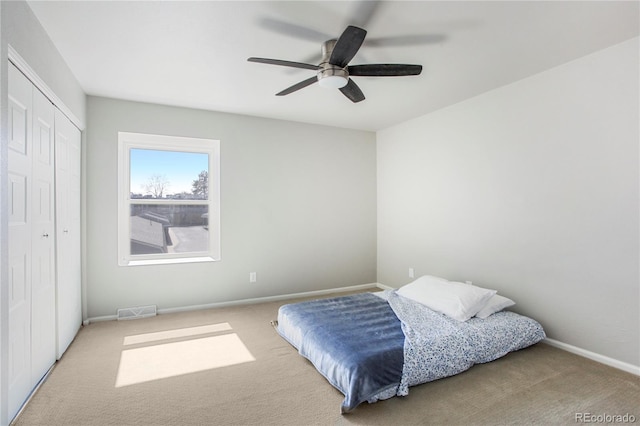 carpeted bedroom with a ceiling fan, baseboards, visible vents, and a closet