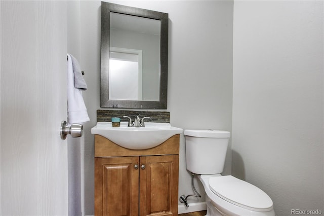 bathroom featuring toilet, backsplash, and vanity