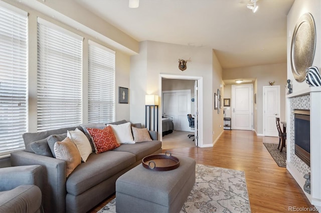 living room with a tile fireplace and light wood-type flooring