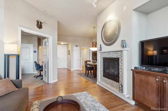 living room with a tile fireplace and light hardwood / wood-style flooring