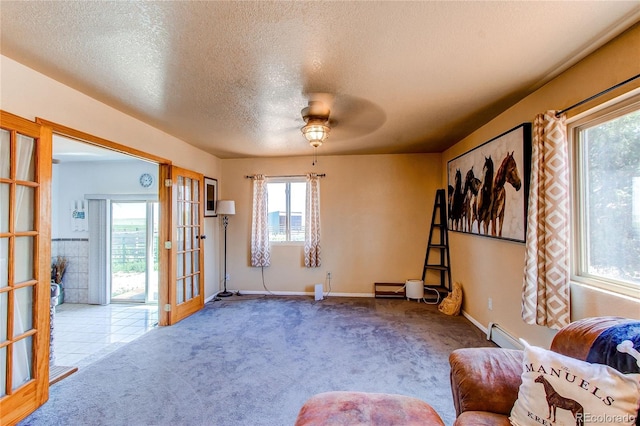 sitting room featuring a wealth of natural light, ceiling fan, light carpet, and a textured ceiling