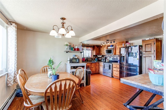 dining space featuring a baseboard heating unit, light hardwood / wood-style floors, a notable chandelier, and sink