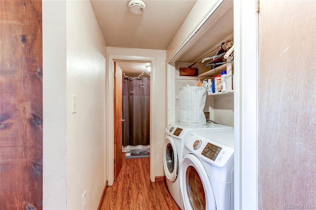 washroom with washer and dryer, a textured ceiling, and light wood-type flooring