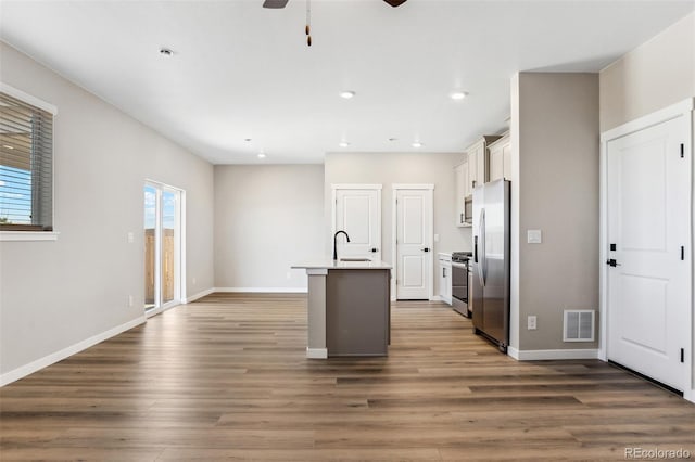 kitchen featuring ceiling fan, white cabinets, visible vents, a kitchen island with sink, and stainless steel appliances