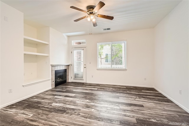 unfurnished living room featuring visible vents, baseboards, ceiling fan, a tiled fireplace, and dark wood finished floors