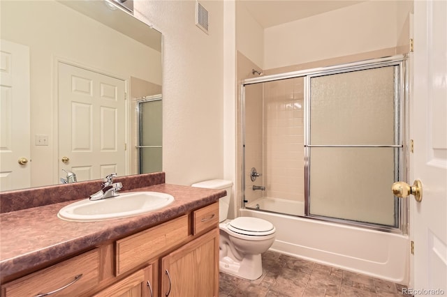 bathroom with visible vents, bath / shower combo with glass door, toilet, and vanity